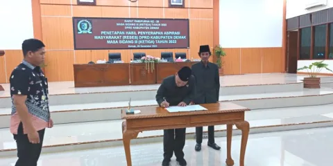 SIMBOLIS: Ketua DPRD Demak, Sri Fahrudin Bisri Slamet saat menandatangani rancangan keputusan DPRD Kabupaten Demak nomor 24 tahun 2022 tentang penyerapan hasil aspirasi masyarakat. (Tomi Budianto/ Lingkarjateng.id)