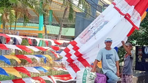 Penjual bendera musiman dari Jawa Barat, Sumantri saat berjualan di trotoar depan SMK Theresiana. Foto: Rifqi/Lingkar.co