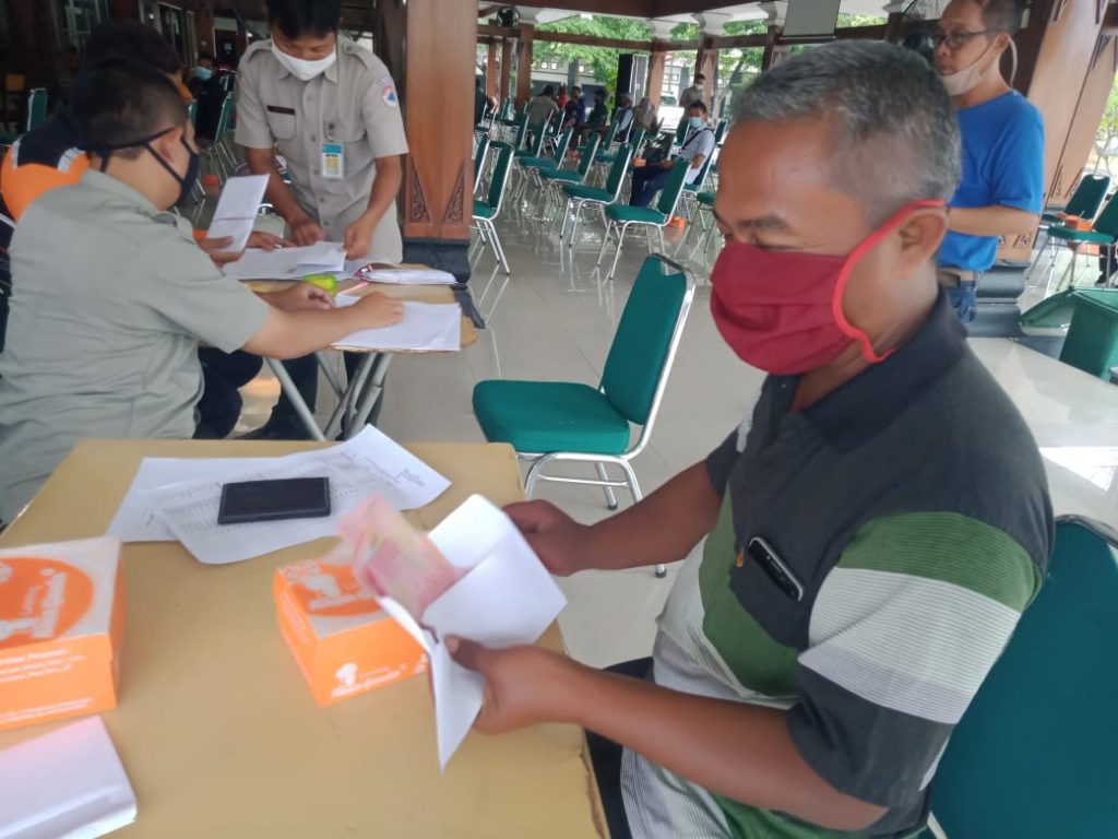 SANTUNAN:Salah satu penerima Bansos dari BPBD Karanganyar tengah menghitung uang yang diperoleh.(PUJOKO/LINGKAR JATENG)