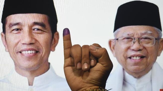 Ilustrasi warga menunjukkan jari usai memberikan hak suara dengan latar poster Joko Widodo-Ma'ruf Amin, Rabu (17/4/2019). (ANTARA/LINGKAR.CO)