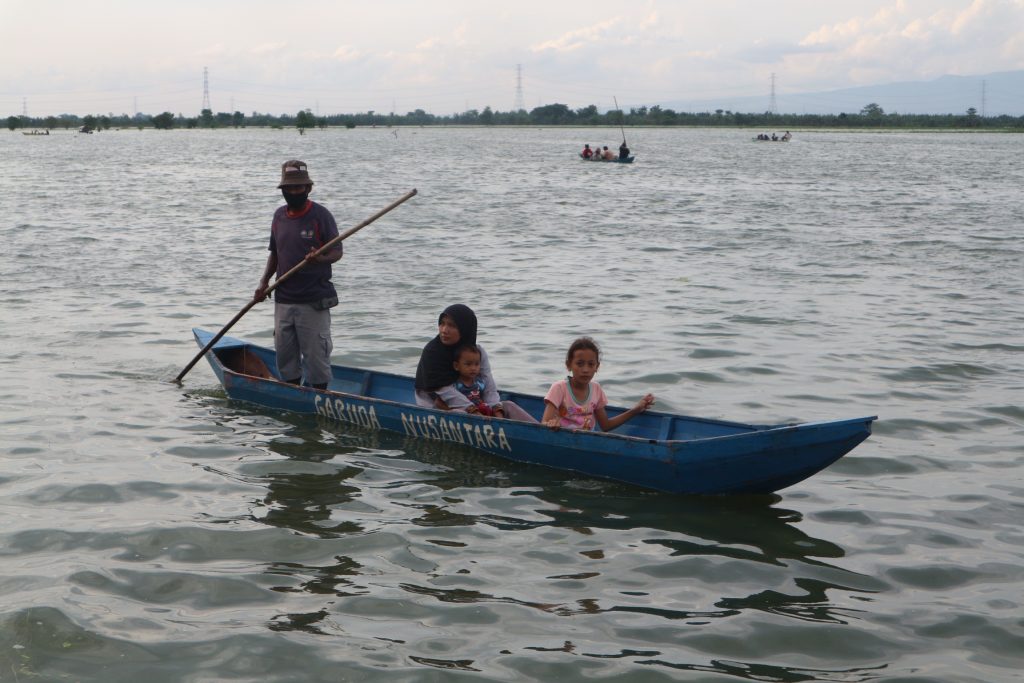 RAMAI: Pengunjung banjir di Desa Pasuruhan, Kecamatan Kayen sedang menaiki perahu untuk mengelilingi sawah yang terkena banjir, Senin (21/12). (FARIDHA NADHIRA/LINGKAR JATENG)
