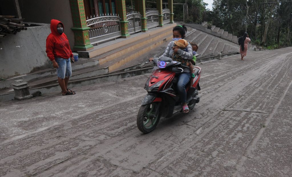 Warga melintasi jalan desa yang tertutup abu vulkanik Gunung Merapi di Beling, Sangup, Tamansari, Boyolali, Jawa Tengah, Rabu (27/1/2021). (KORAN LINGKAR JATENG/LINGKAR.CO)