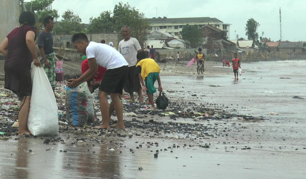 Sejumlah warga tampak mengumpulkan batu bara yang tercecer di Pantai Sekembu, Jum’at (15/1). (MIFTAHUL UMAM/LINGKAR.CO)