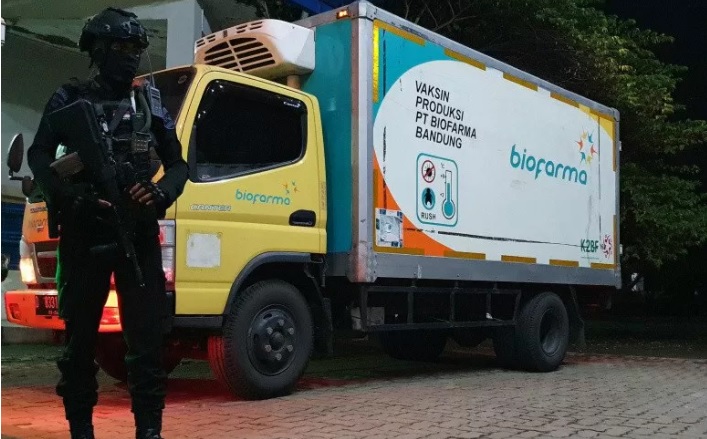 Seorang anggota Brimob Polri bersenjata lengkap menjaga truk boks yang mengangkut puluhan ribu dosis vaksin COVID-19 di Gudang Farmasi Dinas Kesehatan Provinsi Jawa Tengah, Senin (4/1) dini hari. (ANTARA/LINGKAR.CO)