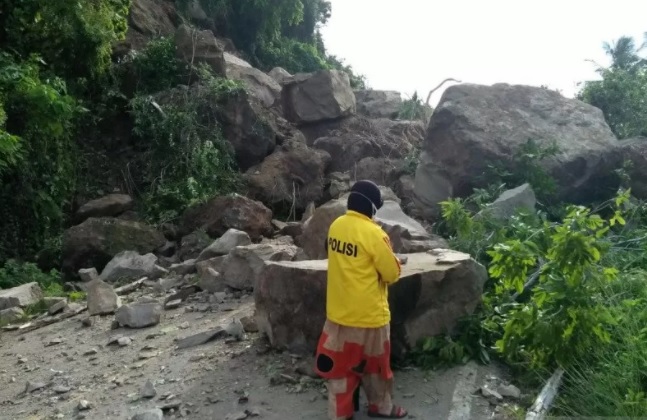 Seorang relawan yang tertahan di Jalan Poros Majene, Kabupaten Sulawesi Barat melihat lebih dekat material longsor yang menutupi badan jalan, Senin (18/1).