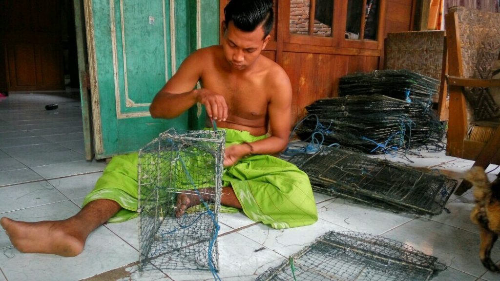Seorang nelayan rajungan saat memperbaiki bobo (alat tangkap rajungan) baru-baru ini. (MIFTAHUS SALAM/LINGKAR.CO)