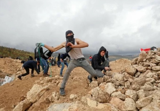 Seorang pengunjuk rasa Palestina, menggunakan ketapel untuk melempar batu ke pasukan Israel, saat protes atas pemukiman Israel di desa al-Mughayyir dekat Ramallah, Tepi Barat, Jumat (15/1/2021). (ANTARA FOTO/LINGKAR.CO)