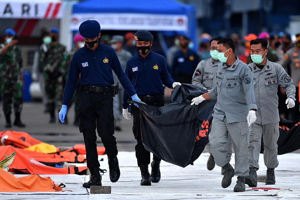 Anggota Bakamla dan Polri membawa kantong jenazah dan serpihan pesawat Sriwijaya Air nomor penerbangan SJ 182 rute Jakarta-Pontianak pada hari kelima operasi SAR pesawat tersebut di Dermaga JICT, Tanjung Priok, Jakarta Utara, Rabu (13/1). ANTARA/LINGKAR.CO)