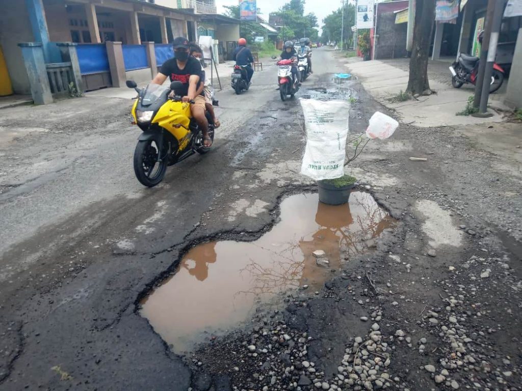 HATI-HATI: Lubang besar di jalan raya Kebakramat-Tasikmadu di Desa Nangsri diberi pot bunga agar pengguna jalan berhati-hati. (PUJOKO/KORAN LINGKAR JATENG)
