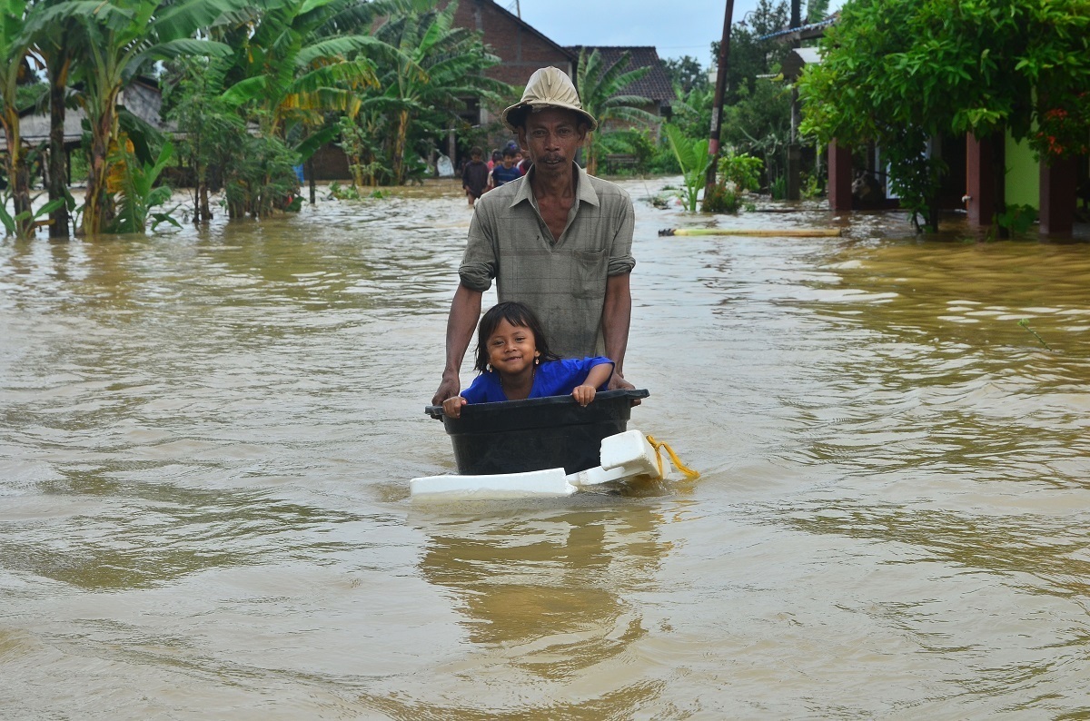 Warga membawa anaknya menggunkan ember melintasi jalan yang terendam banjir di Desa Kedungdowo, Kudus, Jawa Tengah, baru-baru ini. (ANTARA/KORAN LINGKAR JATENG)