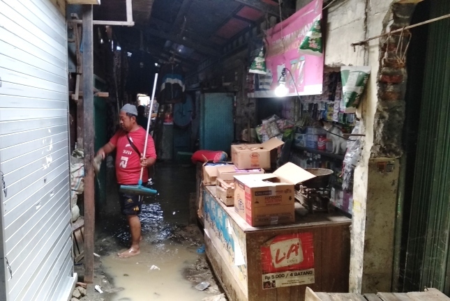 BERTAHAN: Pedagang di Pasar Sayung sedang membersihkan kios yang tergenang air sejak Jumat lalu, Selasa (9/2/2021).(ADITIA ARDIAN/ LINGKAR.CO)