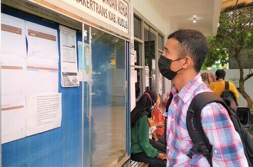 WARGA: Seorang warga sedang melihat papan informasi yang berisi lowongan pekerjaan di kantor Dinas Tenaga Kerja Perindustrian Koperasi UKM Kabupaten Kudus. (ADITIA ARDIAN/ LINGKAR.CO)