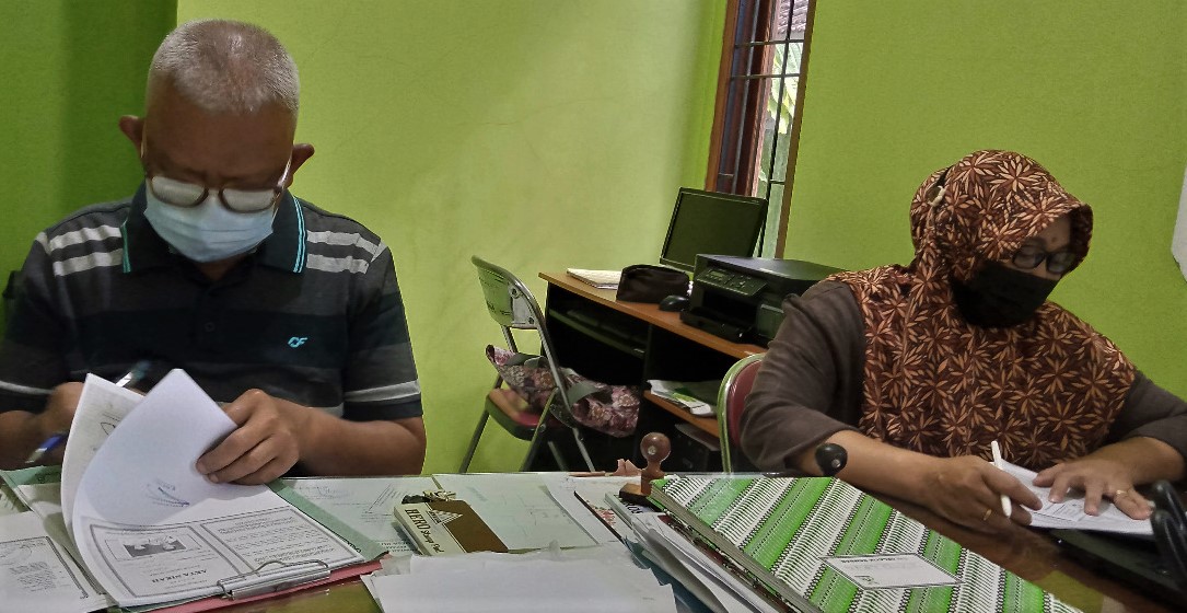 PERIKSA: Kepala Desa Kutoharjo, Kecamatan Pati Hartono (kirim) sedang menandatangi berkas permohonan kependudukan yang diajukan masyarakat belum lama ini. (IBNU MUNTAHA/LINGKAR.CO)