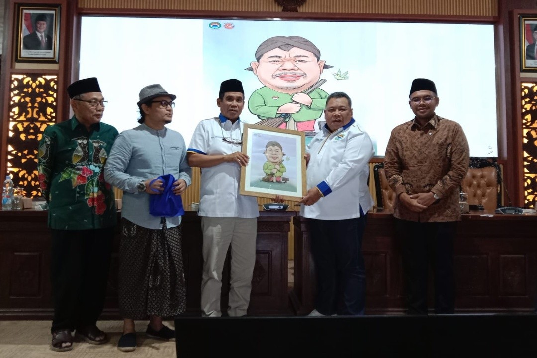 Ketua Umum PB Ika PMII Fathan Subchi menerima karikatur dari Ketua PW Ika PMII Jateng, Musahadi seusai Focus Group Discussion (FGD) Pengentasan Kemiskinan Ekstrem yang digelar di Pendopo Kabupaten Batang, Jumat (26/12/2025).